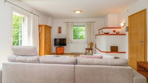 A living room with a sofa, a TV, a wooden cabinet, and a window with curtains.