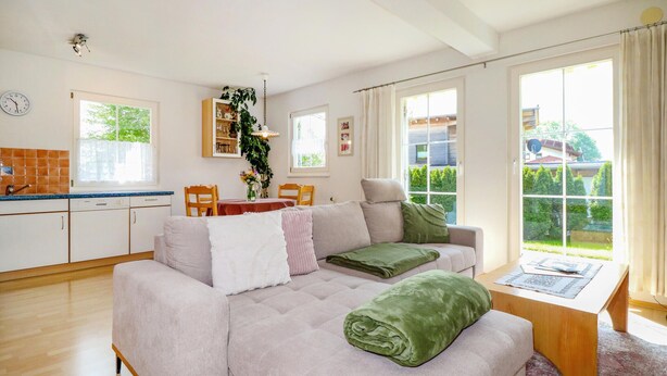 A cozy living room with a sofa, a dining table, and a kitchen area.