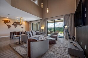 A spacious living room with a large sofa, a coffee table, and a TV mounted on the wall.