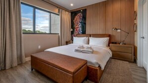 A modern bedroom with a large bed, wooden headboard, and a view of the sky through a window. - Elegant Orlando Getaway Close to Disney (Kissimmee)