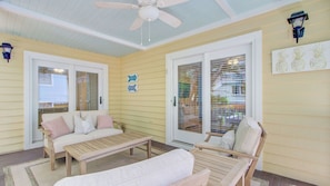 A covered patio with a ceiling fan, a sofa, a chair, and a table. - Steps to Beach & Pool Screened Porch Pelican Bay 45 at Wild Dunes Resort (Isle of Palms)