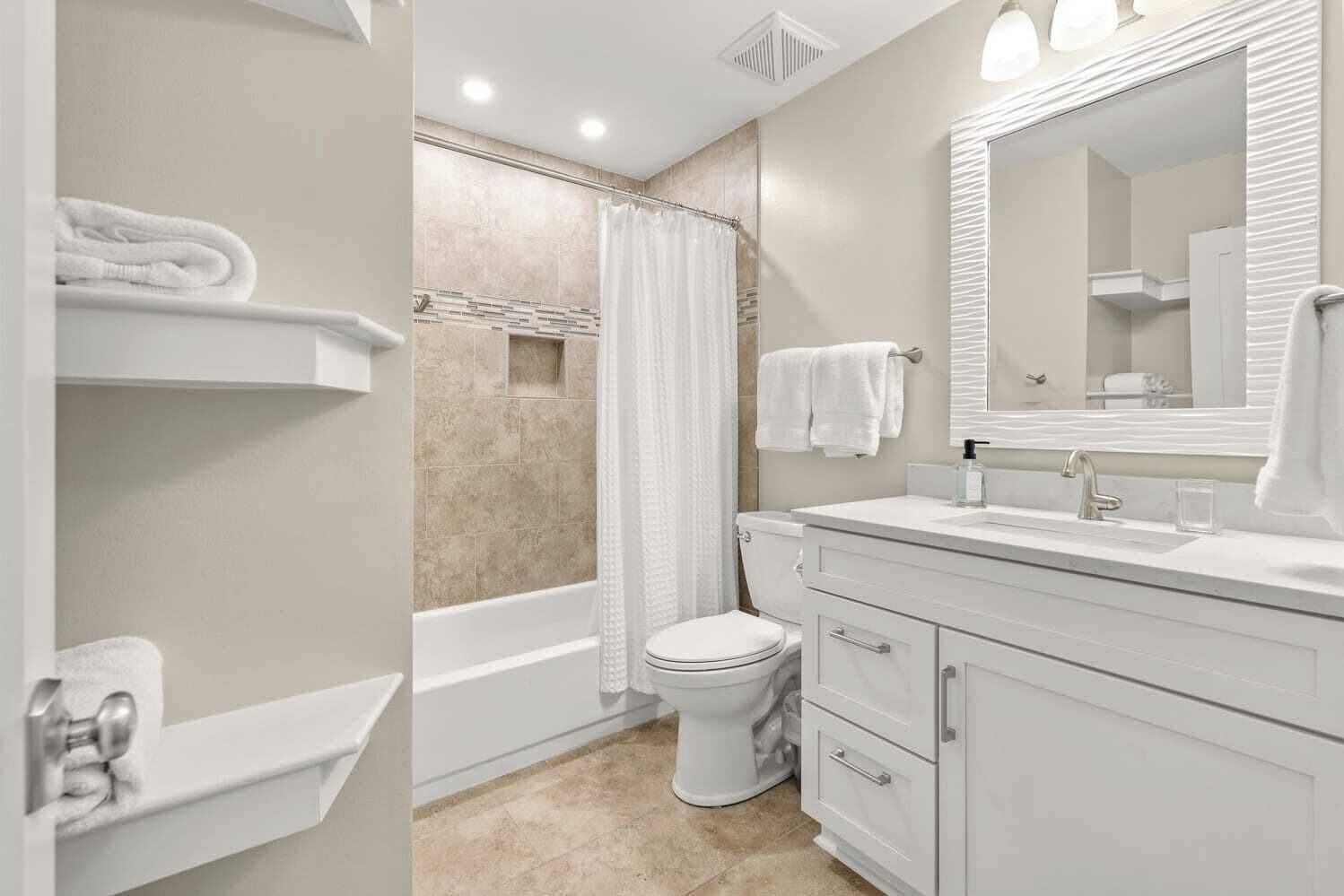 Une salle de bain moderne équipée d’une baignoire, de toilettes et d’un meuble-lavabo.