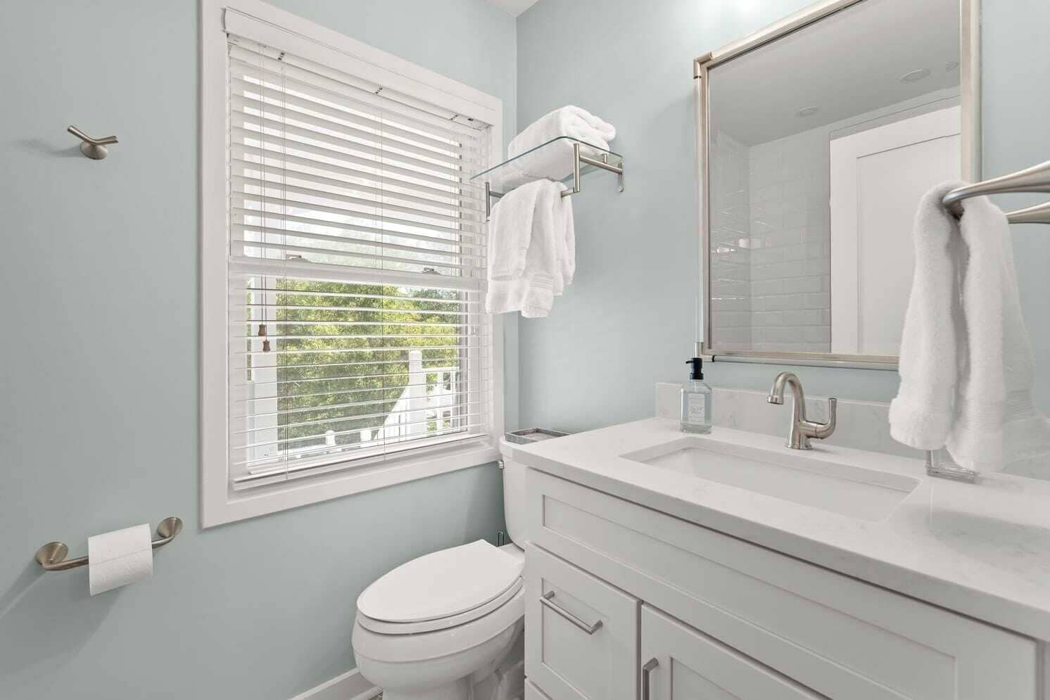 Un baño con inodoro, lavamanos y ventana con persianas.