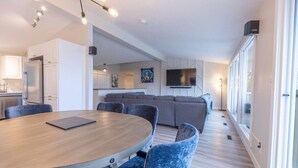 A modern living space with a dining area, kitchen, and a large window providing natural light.