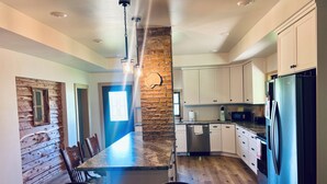 A kitchen with a central island, white cabinets, a stone accent wall, and a blue refrigerator.