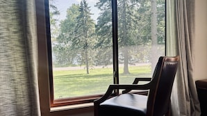 A room with a large window, a wooden floor, and a chair.