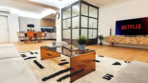 Ein modernes Wohnzimmer mit einer Couch, einem Couchtisch und einem Fernseher, der 'NETFLIX' anzeigt.