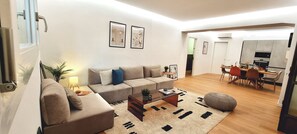 A modern living room with a sofa, coffee table, and rug. There is a dining area with chairs and a table. - Near CityLife & Thermal Baths – Spacious apartment with 2 baths and XL living (Milano)