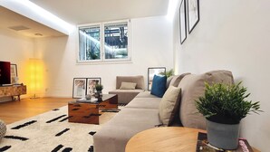 Ein modernes Wohnzimmer mit Flachbildfernseher, einer Couch, einem Couchtisch und einem Topfpflanzen.