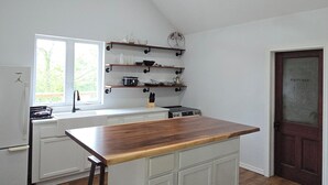 A kitchen with a wooden island, white cabinets, a ceiling fan, and recessed lighting.