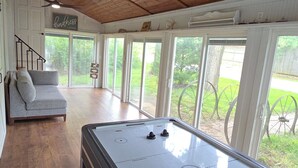 A pool table in a room with wooden ceilings and large windows.