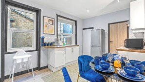 A modern kitchen with white cabinets, a built-in oven, and a large window. - Elegant 2 Bedroom in the Heart of Fulham (London)