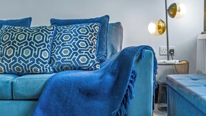 A modern living room with a blue sofa, patterned cushions, and a floor lamp. - Elegant 2 Bedroom in the Heart of Fulham (London)