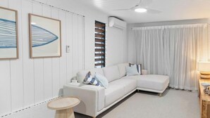 Una sala de estar moderna con un sofá blanco, una mesita redonda y un ventilador de techo.