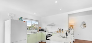 A modern kitchen with a refrigerator, stove, sink, and window.