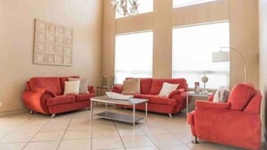 Un salon spacieux avec deux canapés rouges, une table basse et un lustre.
