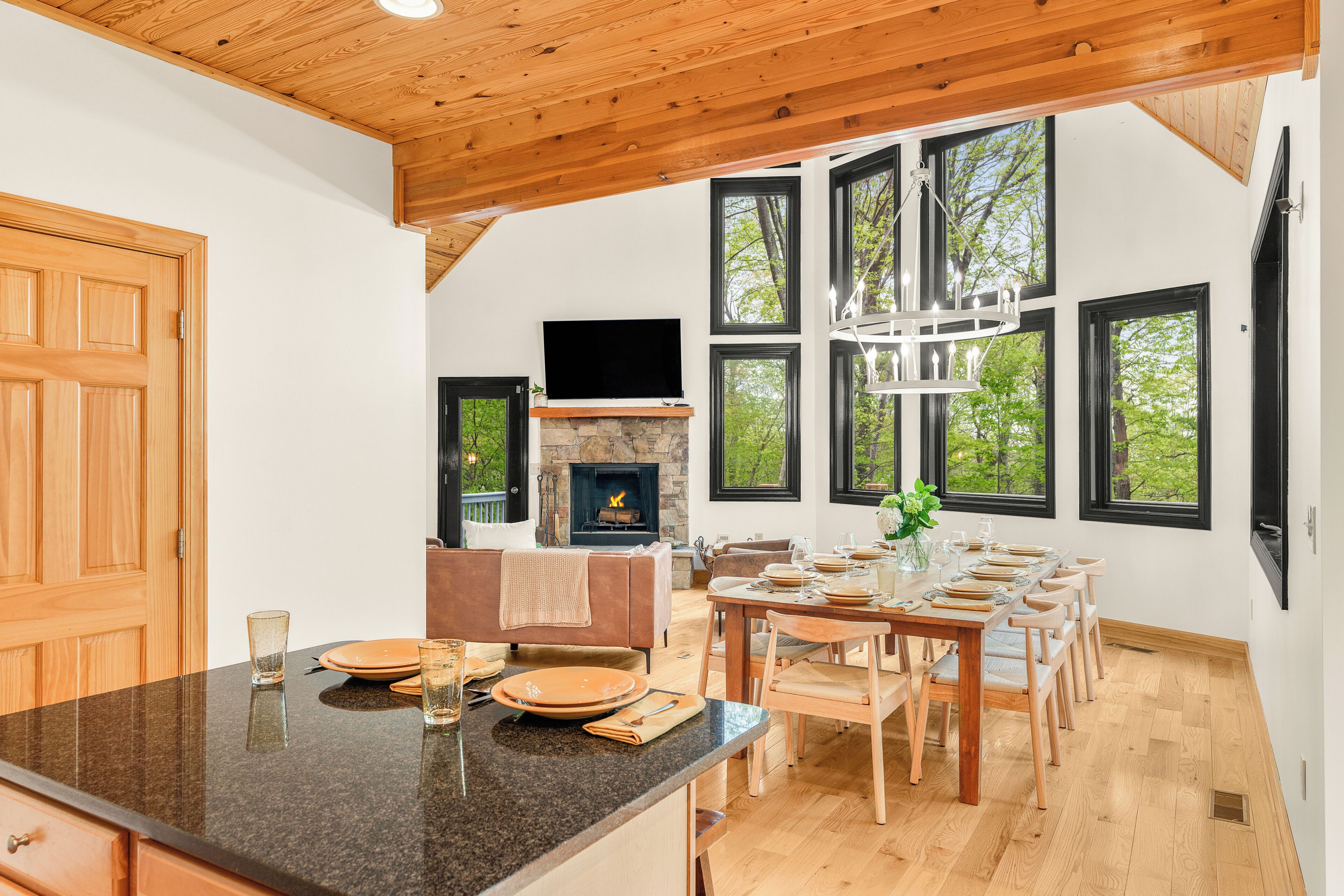 A modern kitchen with a large island, dining area with wooden chairs, and a fireplace.