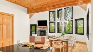 Une cuisine moderne dotée d’un grand îlot central, d’un coin repas avec des chaises en bois et d’une cheminée.