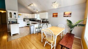 Una cocina moderna con armarios blancos, una mesa de comedor de madera y una lámpara colgante.