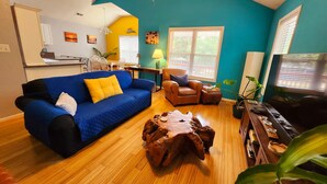 Una sala de estar con un sofá azul, un sillón de cuero marrón y una mesa de centro de madera.