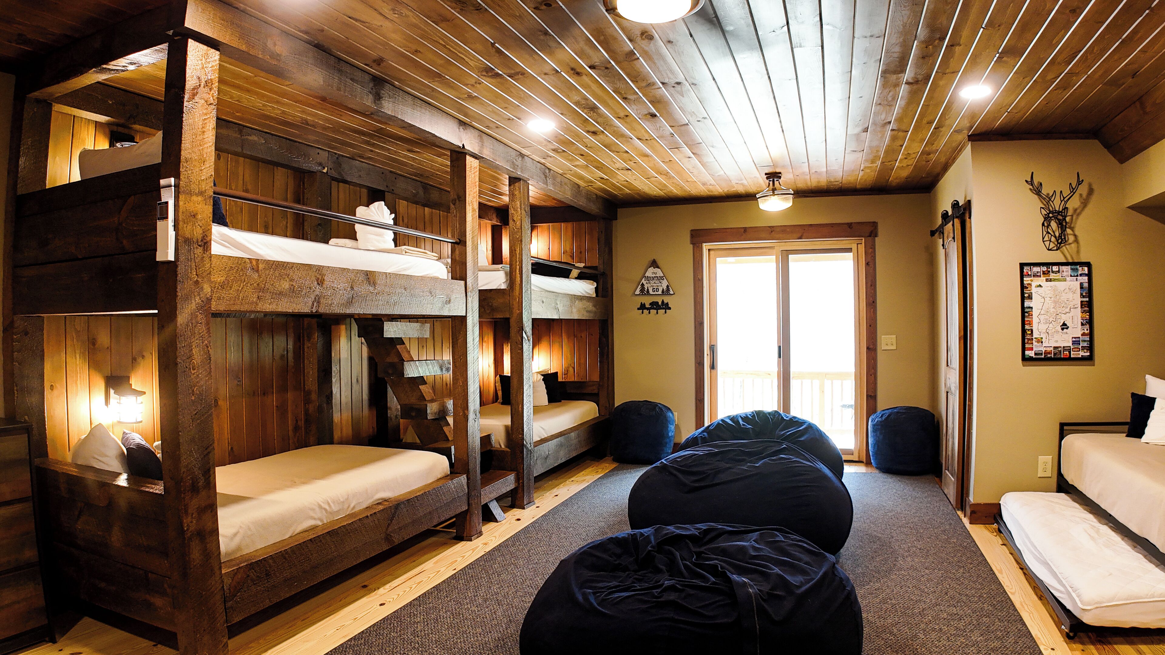 A rustic cabin-style room with bunk beds, a large window, and a map on the wall.