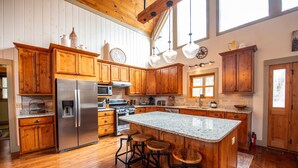 A kitchen with wooden cabinets, stainless steel appliances, a granite countertop, and a large island with stools. - Huge Decks, Hot Tub, Fire Pit & Dog Friendly. Close to Boone and Banner Elk. (Seven Devils)
