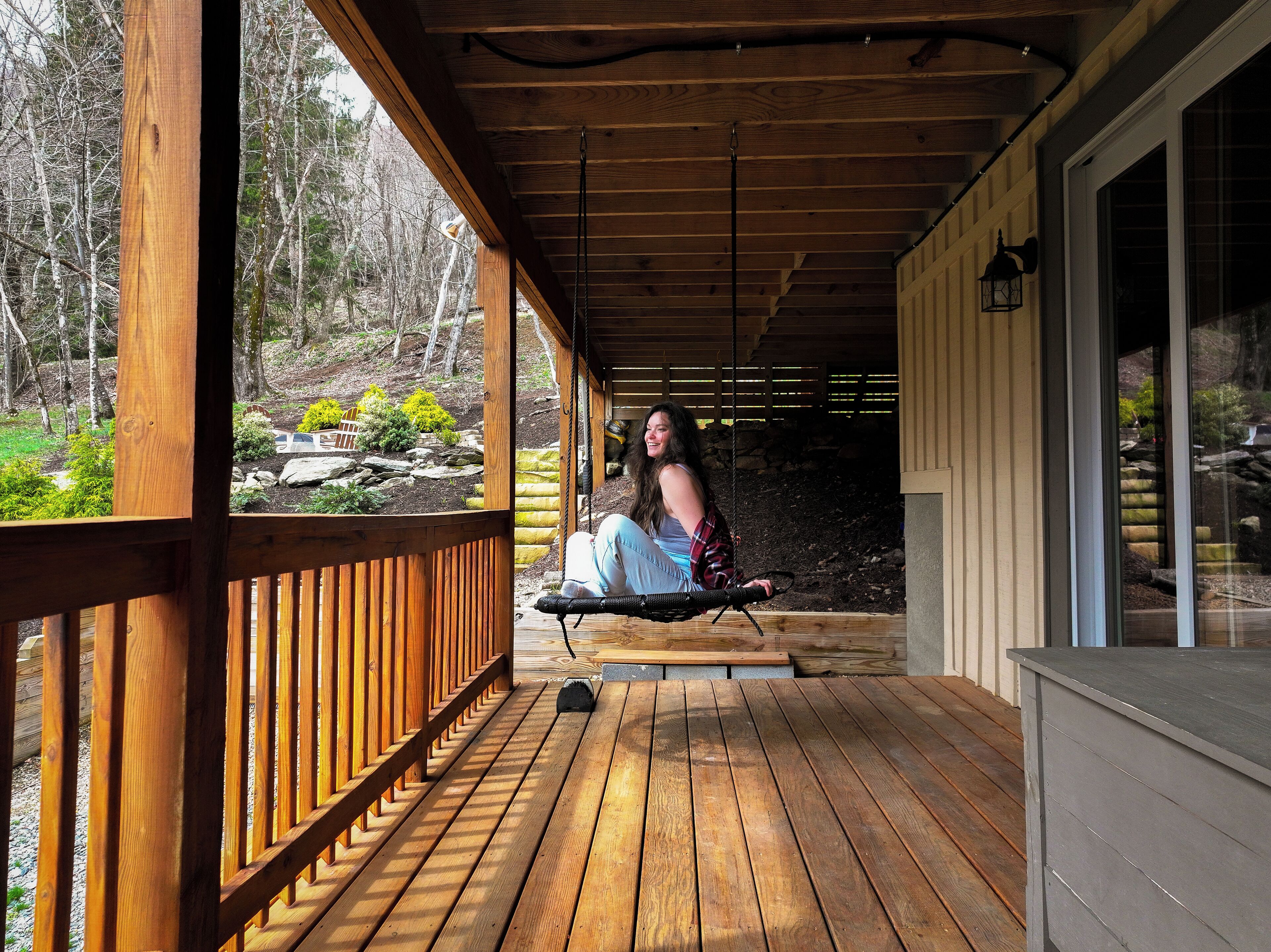 A wooden deck with a person sitting on a swing.