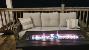 A wicker sofa with cushions and a black fire feature table in front of it. - Riverfront / Fishing / Elk Rail Trails / 4-bedroom house in beautiful Duck (Duck)