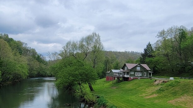 A house with a porch and a river in the background. - Riverfront / Fishing / Elk Rail Trails / 4-bedroom house in beautiful Duck (Duck)