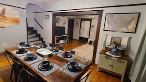 A dining room with a wooden table set for six, a staircase, and a kitchen area visible in the background. - Riverfront / Fishing / Elk Rail Trails / 4-bedroom house in beautiful Duck (Duck)