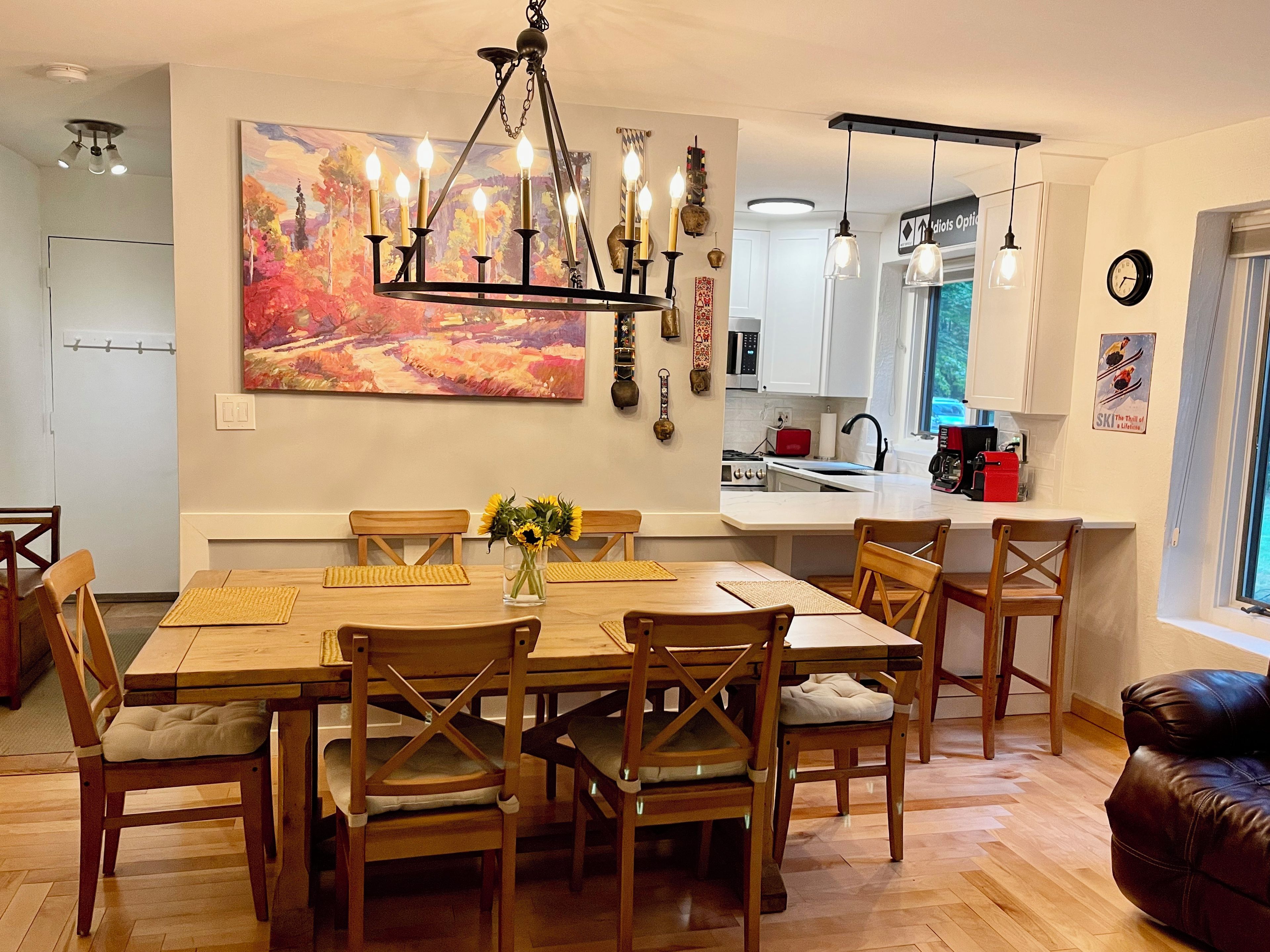 Un coin repas avec une table et des chaises en bois, un lustre et un tableau au mur.