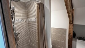 A modern bathroom with a shower, toilet, and a wooden beam ceiling.