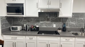 Een moderne keuken met witte kasten, een magnetron, een broodrooster, een koffiezetapparaat en een spoelbak.