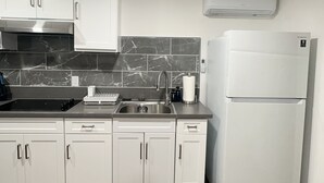 Eine moderne Küche mit weißen Schränken, einer schwarzen Arbeitsplatte, einer Edelstahl-Spüle und einem weißen Kühlschrank.