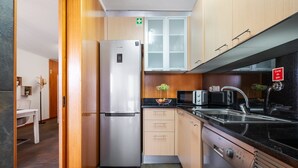 Una cocina moderna con electrodomésticos de acero inoxidable, armarios de madera y una encimera negra.