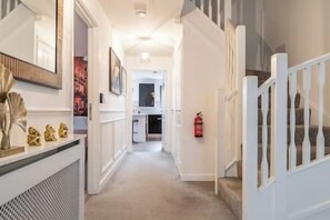Staircase leads to an upper floor, flanked by a console table and mirror.