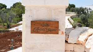 Eine Steinsäule mit einem hölzernen Schild, auf dem "Villa Antichi Saperi" steht.