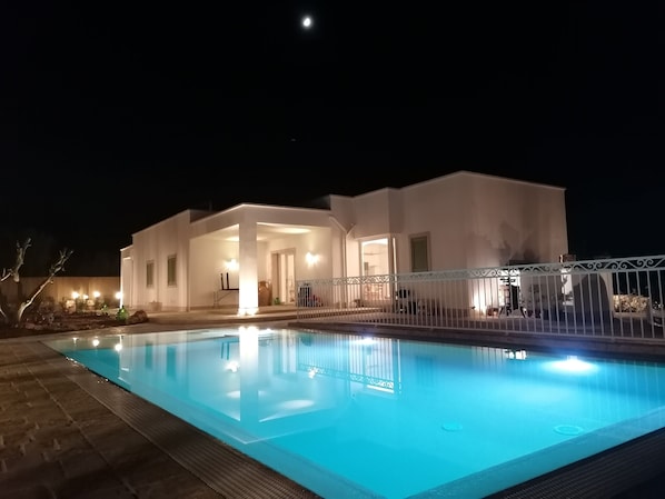 A modern house with a swimming pool at night.