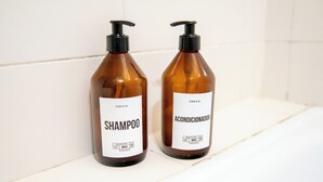 Two bottles of shampoo and conditioner on a white shelf. - Charming studio in beautiful Buenos Aires with AC, WiFi (Buenos Aires)