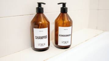 Dos botellas de champú y acondicionador sobre un estante blanco.