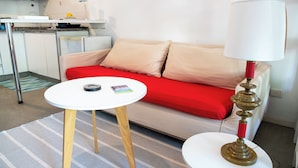 A modern living room with a red sofa, a white table, and a lamp. - Charming studio in beautiful Buenos Aires with AC, WiFi (Buenos Aires)