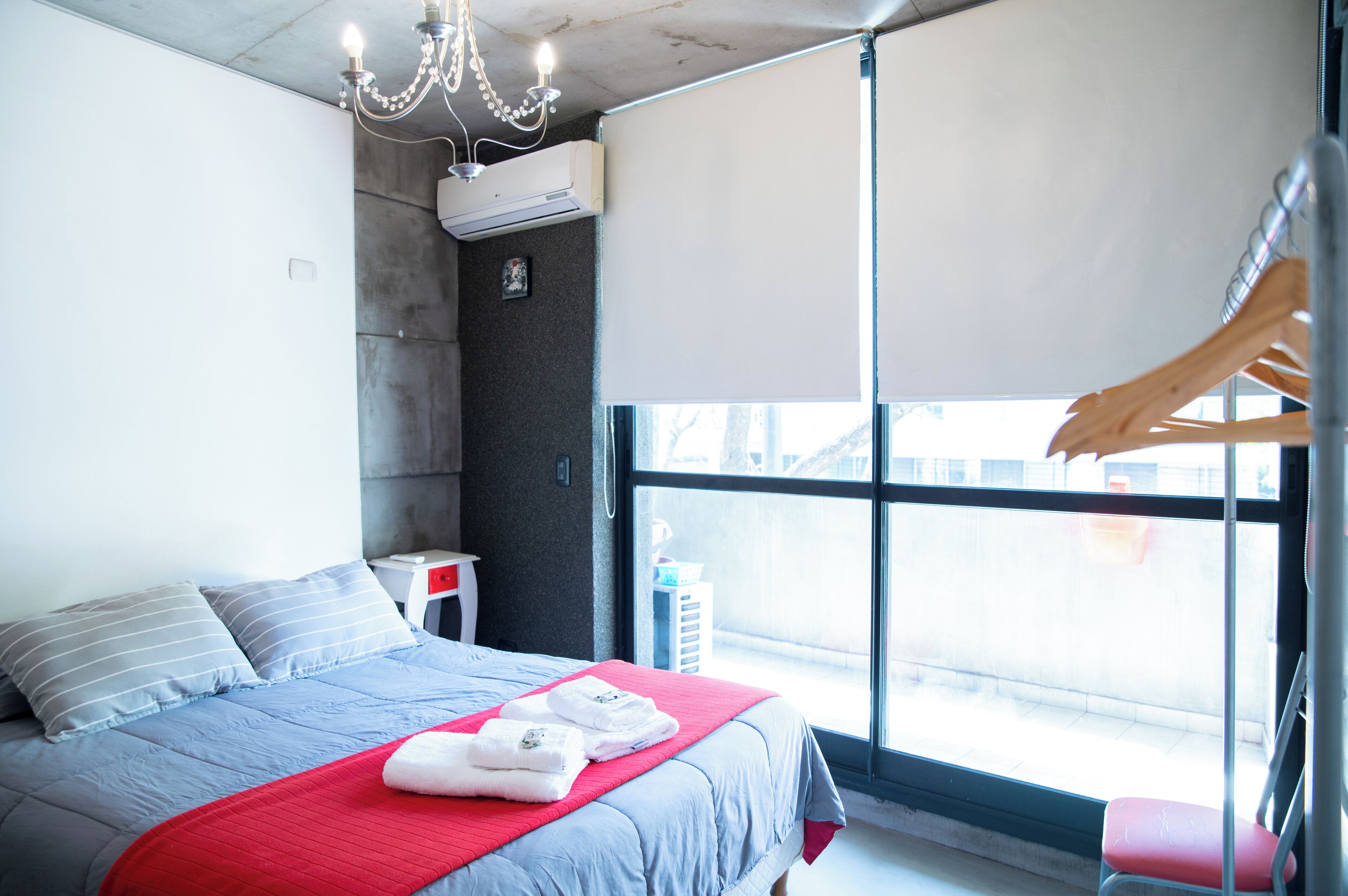Una habitación de hotel moderna con una cama grande, un edredón rojo y vistas por una ventana.