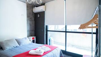 Una habitación de hotel moderna con una cama grande, un edredón rojo y vistas por una ventana.