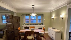 A dining area with a wooden table, chairs, and a rug. There is a window above the sink and a ceiling light fixture. - Charming 1916 Craftsman Near UNC & Historic Downtown Greeley with AC and WiFi (Greeley)