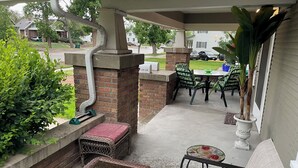 A covered patio area with a brick wall, outdoor furniture, and a small water feature. - Charming 1916 Craftsman Near UNC & Historic Downtown Greeley with AC and WiFi (Greeley)