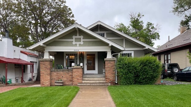 A two-story house with a front porch, a mailbox, and a driveway leading to the entrance. - Charming 1916 Craftsman Near UNC & Historic Downtown Greeley with AC and WiFi (Greeley)