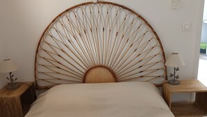 A bed with a bamboo headboard, two bedside tables, and a wall-mounted thermostat. - Quiet country gite with air conditioning.  (Aups)