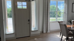 A spacious room with a dining area, a large window with curtains, and a door with a small window. - Quiet 4BR 2.5BA Modern New Country Home in Weatherford (Weatherford)