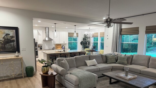 A modern living room with a large sectional sofa, a coffee table, and a dining area with a kitchen in the background. - Quiet 4BR 2.5BA Modern New Country Home in Weatherford (Weatherford)