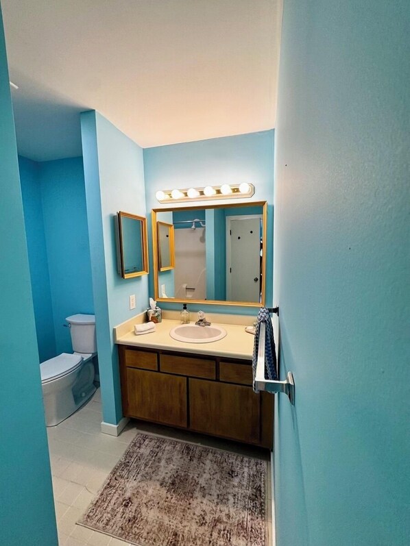 A bathroom with a vanity, sink, and mirror.